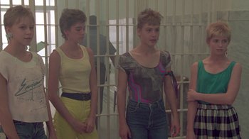 Movie still from “The Legend of Billie Jean” (1985), directed by Matthew Robbins – A group of women standing next to each other in front of a jail cell; Medium shot, Over the shoulder angle