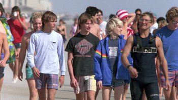 Movie still from “The Legend of Billie Jean” (1985), directed by Matthew Robbins – A group of young men walking down a sidewalk; Medium shot, Low angle