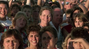 Movie still from “The Legend of Billie Jean” (1985), directed by Matthew Robbins – A large group of people gathered together for a concert; Close Up shot, High angle