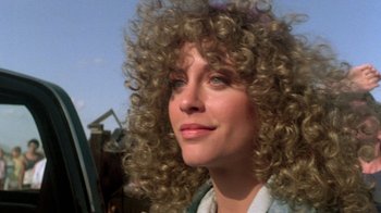 Movie still from “The Legend of Billie Jean” (1985), directed by Matthew Robbins – A person with curly blonde hair; Close Up shot, Over the shoulder angle