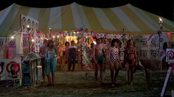 Movie still from “The Legend of Billie Jean” (1985), directed by Matthew Robbins – A group of people standing under a striped tent; Wide shot, High angle
