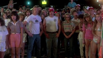 Movie still from “The Legend of Billie Jean” (1985), directed by Matthew Robbins – A group of people standing in front of each other; Wide shot, High angle