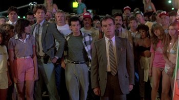 Movie still from “The Legend of Billie Jean” (1985), directed by Matthew Robbins – A group of men standing in a crowd of people; Wide shot, Low angle
