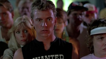 Movie still from “The Legend of Billie Jean” (1985), directed by Matthew Robbins – A man in a black shirt is looking at the camera; Close Up shot, Low angle