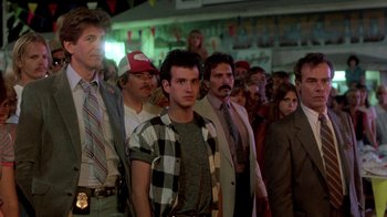 Movie still from “The Legend of Billie Jean” (1985), directed by Matthew Robbins – A group of men and women standing in a room; Medium shot, Low angle