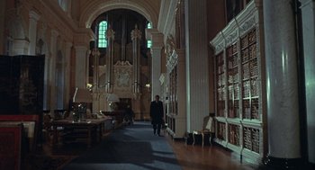 Movie still from “The Legend of Hell House” (1973), directed by John Hough – A man walking down the hall of a library; Extreme Wide shot, Low angle