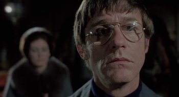 Movie still from “The Legend of Hell House” (1973), directed by John Hough – A person wearing glasses; Close Up shot, Low angle