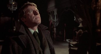 Movie still from “The Legend of Hell House” (1973), directed by John Hough – A man wearing a suit and tie looking up at the sky; Close Up shot, Low angle