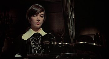 Movie still from “The Legend of Hell House” (1973), directed by John Hough – A woman in a black and white dress looking into a mirror; Close Up shot, High angle