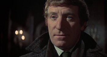 Movie still from “The Legend of Hell House” (1973), directed by John Hough – A person wearing a suit and tie; Close Up shot, Low angle