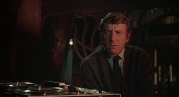 Movie still from “The Legend of Hell House” (1973), directed by John Hough – A man sitting at a table in front of a mirror; Close Up shot, Low angle