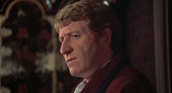 Movie still from “The Legend of Hell House” (1973), directed by John Hough – A person wearing a red jacket; Close Up shot, Low angle