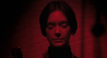 Movie still from “The Legend of Hell House” (1973), directed by John Hough – A woman with her eyes closed in a dark room; Close Up shot, Low angle
