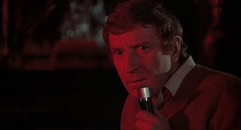 Movie still from “The Legend of Hell House” (1973), directed by John Hough – A man holding a microphone in his hand; Close Up shot, Low angle