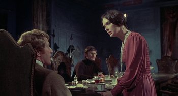 Movie still from “The Legend of Hell House” (1973), directed by John Hough – A group of people sitting around a table; Medium shot, Over the shoulder angle