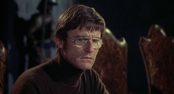 Movie still from “The Legend of Hell House” (1973), directed by John Hough – A man wearing glasses and a brown sweater; Close Up shot, Low angle