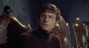 Movie still from “The Legend of Hell House” (1973), directed by John Hough – A man in a brown sweater wearing glasses; Close Up shot, Low angle