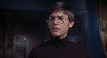Movie still from “The Legend of Hell House” (1973), directed by John Hough – A man in a black sweater and glasses; Close Up shot, Low angle