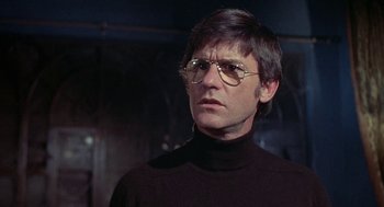 Movie still from “The Legend of Hell House” (1973), directed by John Hough – A man wearing glasses and a black sweater; Close Up shot, Low angle
