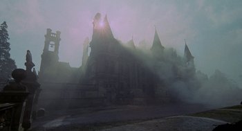 Movie still from “The Legend of Hell House” (1973), directed by John Hough – The sun is shining through the fog in front of a building; Extreme Wide shot, High angle