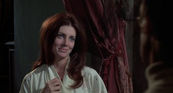 Movie still from “The Legend of Hell House” (1973), directed by John Hough – A woman with long red hair standing in front of a curtain; Close Up shot, Over the shoulder angle