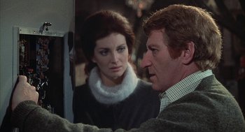 Movie still from “The Legend of Hell House” (1973), directed by John Hough – A man and a woman looking at each other in front of a mirror; Close Up shot, Over the shoulder angle