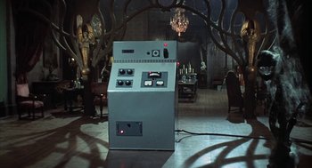Movie still from “The Legend of Hell House” (1973), directed by John Hough – An electrical device in the middle of a dark room; Wide shot, High angle