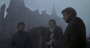 Movie still from “The Legend of Hell House” (1973), directed by John Hough – A group of people standing on a foggy day; Medium shot, Low angle
