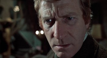 Movie still from “The Legend of Hell House” (1973), directed by John Hough – A man's face in a dimly - lit room; Close Up shot, Low angle