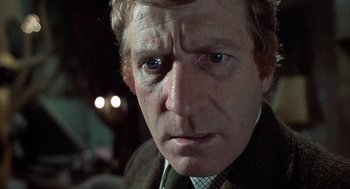 Movie still from “The Legend of Hell House” (1973), directed by John Hough – A person wearing a suit and tie; Close Up shot, Low angle