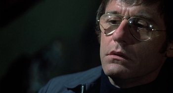 Movie still from “The Legend of Hell House” (1973), directed by John Hough – A person wearing glasses; Close Up shot, Low angle