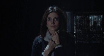 Movie still from “The Legend of Hell House” (1973), directed by John Hough – A woman in a dark room holding her collar; Close Up shot, Low angle