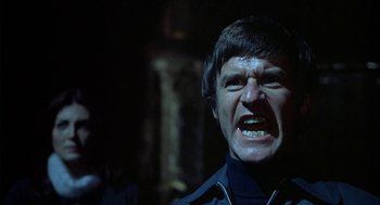 Movie still from “The Legend of Hell House” (1973), directed by John Hough – A man with a beard is yelling at the camera; Close Up shot, Low angle