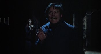 Movie still from “The Legend of Hell House” (1973), directed by John Hough – A man in a black jacket is clapping; Medium shot, Low angle