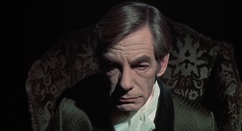 Movie still from “The Legend of Hell House” (1973), directed by John Hough – A person sitting on a couch; Close Up shot, High angle