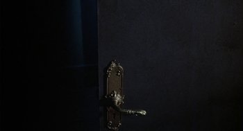 Movie still from “The Legend of Hell House” (1973), directed by John Hough – A door handle is shown in a dark room; Extreme Close Up shot, High angle