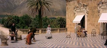 Movie still from “The Leopard” (1963), directed by Luchino Visconti – A woman dressed in period clothing standing in a courtyard; Extreme Wide shot, High angle
