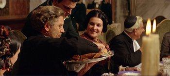 Movie still from “The Leopard” (1963), directed by Luchino Visconti – A man holding a plate with food on top of it while a woman looks on; Medium shot, Over the shoulder angle