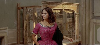 Movie still from “The Leopard” (1963), directed by Luchino Visconti – A woman in a pink dress is posing for a picture; Medium shot, Low angle