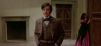 Movie still from “The Leopard” (1963), directed by Luchino Visconti – A man in a suit and bow tie standing in front of a door; Medium shot, Low angle