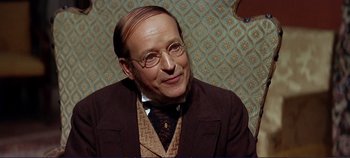 Movie still from “The Leopard” (1963), directed by Luchino Visconti – An old man with a goatee and glasses is smiling; Close Up shot, Over the shoulder angle