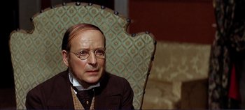 Movie still from “The Leopard” (1963), directed by Luchino Visconti – An older man sitting in a chair wearing glasses; Close Up shot, Over the shoulder angle