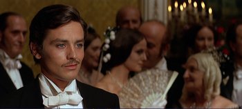 Movie still from “The Leopard” (1963), directed by Luchino Visconti – A group of people in formal wear standing next to each other; Close Up shot, Over the shoulder angle