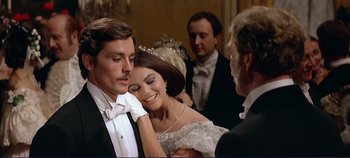Movie still from “The Leopard” (1963), directed by Luchino Visconti – A man and a woman in formal wear standing next to each other in front of other people; Close Up shot, Over the shoulder angle