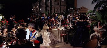 Movie still from “The Leopard” (1963), directed by Luchino Visconti – A group of people sitting at a table with candles; Wide shot, Over the shoulder angle
