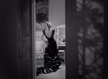 Movie still from “The Leopard Man” (1943), directed by Jacques Tourneur – A woman in a black dress standing in a room; Wide shot, Over the shoulder angle