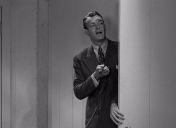 Movie still from “The Leopard Man” (1943), directed by Jacques Tourneur – An old photo of a man in a suit holding a microphone; Medium shot, Low angle