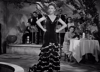 Movie still from “The Leopard Man” (1943), directed by Jacques Tourneur – A woman in a black and white photo is wearing a black dress; Medium shot, Low angle