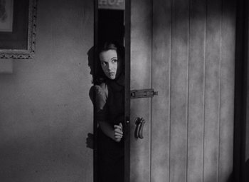 Movie still from “The Leopard Man” (1943), directed by Jacques Tourneur – A woman standing at the door of a room; Medium shot, High angle