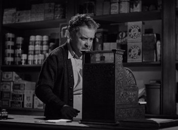 Movie still from “The Leopard Man” (1943), directed by Jacques Tourneur – An older man sitting in front of an open laptop computer; Medium shot, Low angle